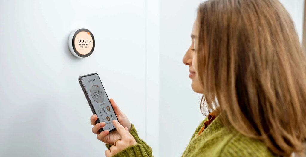 Thermostat intelligent moderne montré sur mur résidentiel affichant interface de programmation horaire dans intérieur chaleureux de maison québécoise